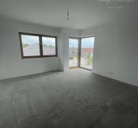 Ein leerer Raum mit Fenstern und Betonboden in einem Einfamilienhaus.