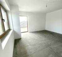 Ein unmöbliertes Zimmer in einem Einfamilienhaus mit Betonboden und Fenstern.