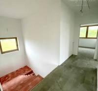 Innenraum eines Einfamilienhauses mit Betontreppen und großen Fenstern für natürliches Licht.