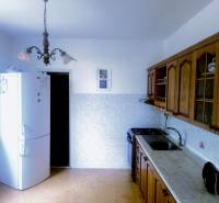 Küche in einer 3-Zimmer-Wohnung mit rustikalen Holzschränken und einem weißen Kühlschrank.