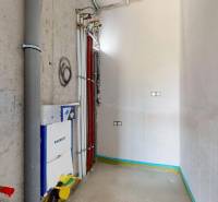 Ein leeres Badezimmer im Erdgeschoss eines Einfamilienhauses mit Installationen und Rohrleitungen.