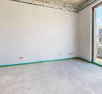 Ein Zimmer in einem Einfamilienhaus mit Betonboden und einem großen Fenster.