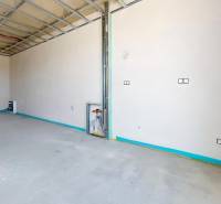 Ein unverputzter Raum mit Installation in einem Einfamilienhaus, freiliegende Decke und Terrassentüren.
