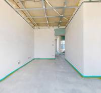 Ein leerer Innenraum mit Betonboden und unfertiger Decke in einem Einfamilienhaus.
