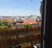 Balkon in einer 3-Zimmer-Wohnung mit Rattanmöbeln und Blick auf die Dächer.