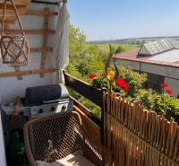 Balkon einer 3-Zimmer-Wohnung mit Sitzgelegenheit, Grill und Blick ins Grüne in Pezinok.