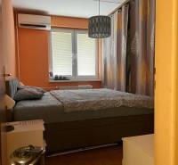 Schlafzimmer in einer 3-Zimmer-Wohnung mit Doppelbett, orangefarbenen Wänden und Klimaanlage.