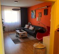 Wohnzimmer einer 3-Zimmer-Wohnung mit orangefarbener Wand, Sofa und Couchtisch.