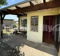 Der Hof des Einfamilienhauses in Mojmírovce, mit einem Unterstand, einem Tisch und Holzelementen.