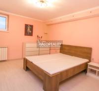 Schlafzimmer mit Bett in einer 2-Zimmer-Wohnung mit geräumiger Kommode und pastellrosa Wand.