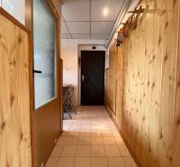 Holzverkleidung im Flur einer 2-Zimmer-Wohnung, helle Fliesen, klappbare Stühle.