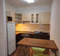 Küche mit Geräten, Holzarbeitsplatte und Esstisch in einer Zweizimmerwohnung.