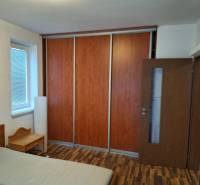 Schlafzimmer in einer 2-Zimmer-Wohnung mit Holzboden, Kleiderschrank und Bett.