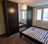 Schlafzimmer in einer 2-Zimmer-Wohnung mit dunklem Kleiderschrank, Bett und Fenster.
