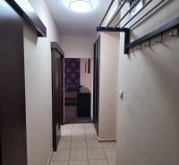 Ein enger Flur in einer 2-Zimmer-Wohnung mit Keramikfliesen und einem klappbaren Garderobensystem.