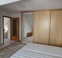 Schlafzimmer im Einfamilienhaus mit einem Holzschrank und offenen Türen zum Flur.