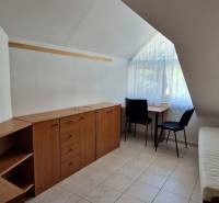 Ein Zimmer in einem Einfamilienhaus mit Stauraum, zwei Stühlen und einem Fenster mit Vorhängen.