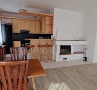 Wohnzimmer in einem Einfamilienhaus mit Kamin, Küche und Holzmöbeln.