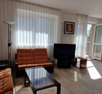 Wohnzimmer mit orangenen Möbeln, Fernseher und großen Fenstern, Einfamilienhaus.