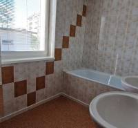 Badezimmer mit Badewanne und Waschbecken in einem Einfamilienhaus, mit Fliesen und Fenster.