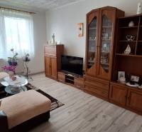 Wohnzimmer in einer 3-Zimmer-Wohnung mit Sofa, Schrank und Fernseher, helle Dekoration.