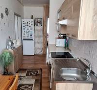 Küche in einer 3-Zimmer-Wohnung mit Holzmöbeln und Deckenventilator.