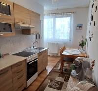 Küche in einer 3-Zimmer-Wohnung mit Holzschränken und Esstisch, helle Dekoration.