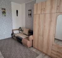 Wohnzimmer in einer 3-Zimmer-Wohnung mit Sofa, Schrank und Wanddekorationen.