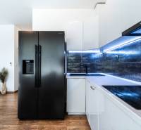 Küche in einer 2-Zimmer-Wohnung mit einem schwarzen Kühlschrank, einer modernen Küchenzeile und Holzboden.