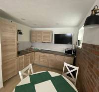 Küche in einem Einfamilienhaus mit Holzmöbeln, Esstisch und Ziegelwand.
