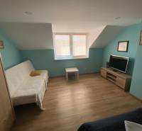 Ein Zimmer in einem Einfamilienhaus mit einem Sofa, einem Fernseher und einem Holzboden.