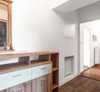 Kommode mit Holzspiegel im Flur einer 2-Zimmer-Wohnung, die zu einem hellen Korridor führt.