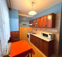 Küche in einer 3-Zimmer-Wohnung mit Holzschränken und Esstisch.