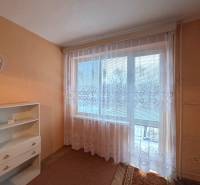 Ein Zimmer in einer 3-Zimmer-Wohnung mit orangefarbenen Wänden und weißen Vorhängen am Fenster.
