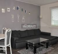Wohnzimmer mit dunklem Sofa und Esstisch in einer 3-Zimmer-Wohnung, dekorative Bilder an der Wand.