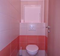 Toilette mit Fliesen in einer orange-weißen Kombination in einer 2-Zimmer-Wohnung.