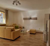 Wohnzimmer in einer 2-Zimmer-Wohnung mit gelbem Sofa und Holzboden.