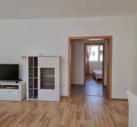 Wohnzimmer mit Fernseher, weißen Möbeln und Blick ins Schlafzimmer, 2-Zimmer-Wohnung.