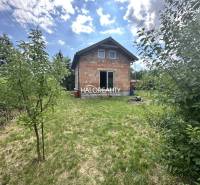 Eine Hütte in Vinosady mit einem großen Garten und einem Holzbau unter blauem Himmel.