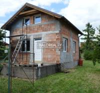 Eine Hütte in Vinosady, gebaut aus Ziegeln, mit einer Leiter und grüner Umgebung.