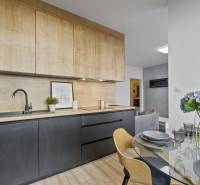 Küche in einer 2-Zimmer-Wohnung mit Holzschränken, Esstisch mit Blumen.