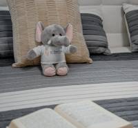 Ein Elefantenspielzeug auf einem Kissen mit einem Buch auf dem Bett in einer Zweizimmerwohnung.