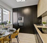 Küche in einer 2-Zimmer-Wohnung mit Esstisch und moderner schwarzer Küchenzeile.