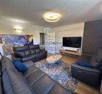 Wohnzimmer in einem Einfamilienhaus mit schwarzen Sofas, Fernseher und abstraktem Bild an der Wand.