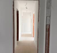 Ein Flur in einem Einfamilienhaus mit ungestrichenen Türen und hängender Beleuchtung.