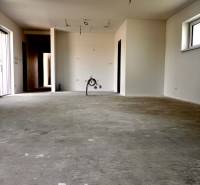 Ein leerer Raum mit Betonboden, bereit zur Fertigstellung in einem Einfamilienhaus.