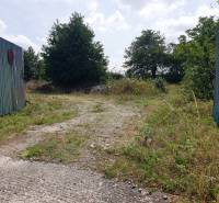 Eingezäunter Zugang zu Gewerbegrundstücken in Trenčianske Bohuslavice mit Grünflächen und Gehweg.
