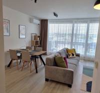 Das Wohnzimmer in der 3-Zimmer-Wohnung enthält ein Sofa, einen Esstisch und ein großes Fenster.