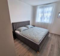 Schlafzimmer mit grauem Bett und hellen Möbeln in einer 3-Zimmer-Wohnung.