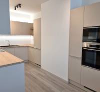 Moderne Küche in einer 3-Zimmer-Wohnung mit Holzarbeitsplatte und eingebauten Geräten.